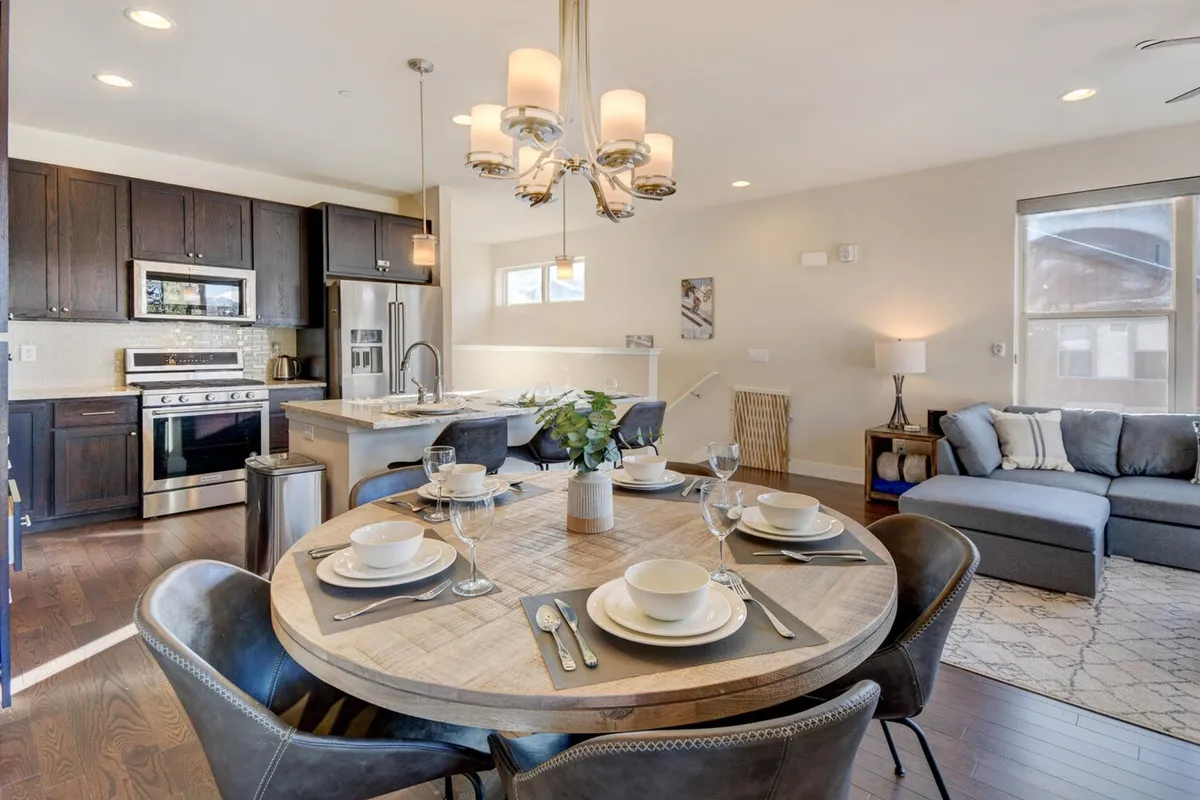 A cozy, sunlit interior with a dining table, modern kitchen appliances, and a comfortable sofa. The scene sets the mood for family meals, social gatherings, and relaxed moments, with plenty of space for guests to come together.