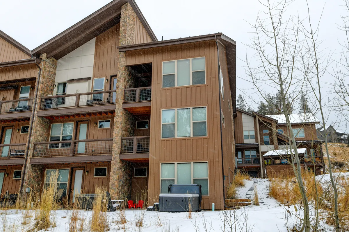 A striking exterior view of the villa, featuring rustic wooden architecture, stone accents, balconies, and a snow-covered ground. The scene conveys a warm, welcoming ambiance with hints of cozy indoor spaces and an outdoor environment ready for seasonal adventures.
